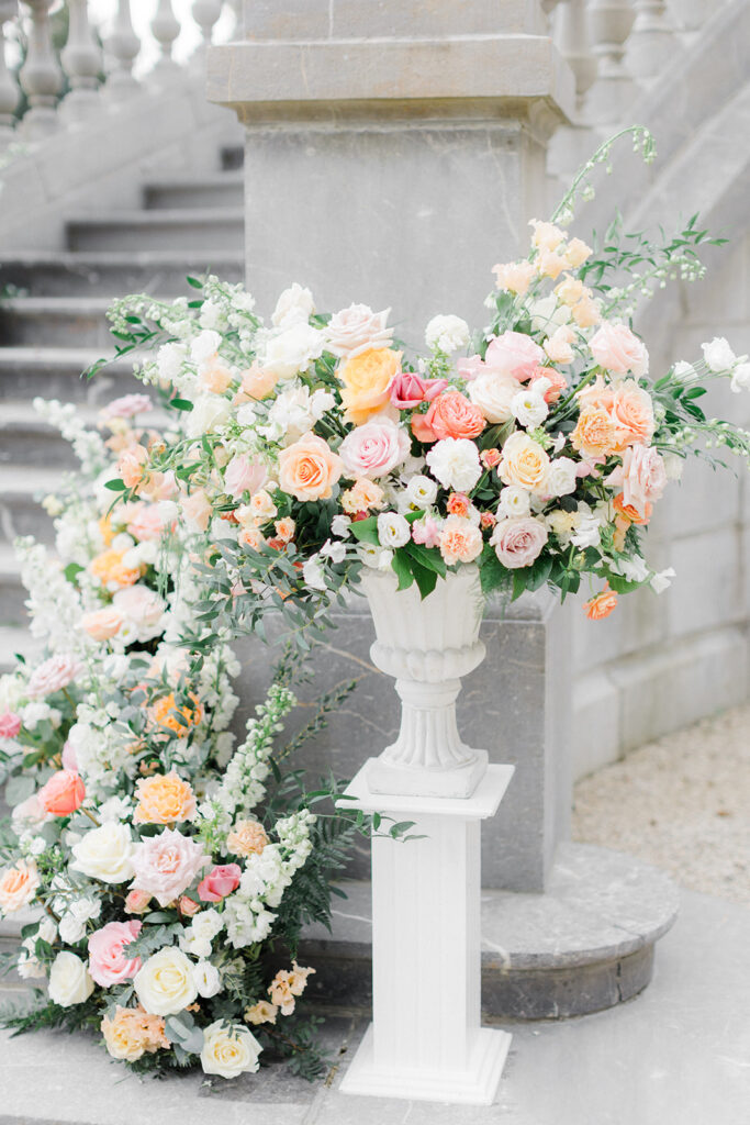 Peach Fuzz Pantone Colour of the Year Wedding flowers luxury florist Flourish and Grace photography by Natalie Stevenson in Paris at Chateau Bouffemont. Flower urns and meadows on steps