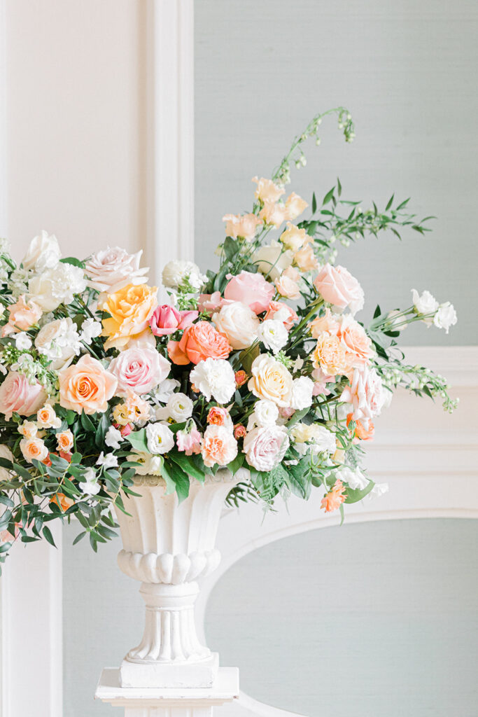 Peach Fuzz Pantone Colour of the Year Wedding flowers luxury florist Flourish and Grace photography by Natalie Stevenson in Paris at Chateau Bouffemont. Flower urns in ballroom